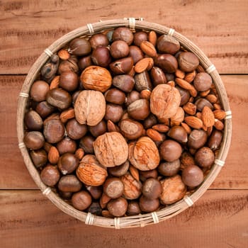 Mixed different kinds of nuts in shells ,cashew, almond, walnut, hazelnut, pistachio, hazelnuts, pecan and  macadamia in the busket on rustic wooden background.