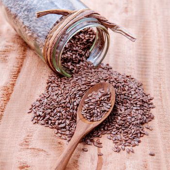 Alternative health care and dieting flax seeds in wooden spoon set up on rustic wooden background.