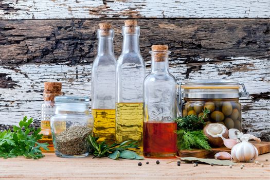 Different sorts of cooking oil,olive oil flavored and Sesame oil with spices herb rosemary ,thyme,dill,sage and parsley set up with old wooden background.