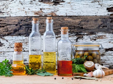 Different sorts of cooking oil,olive oil flavored and Sesame oil with spices herb rosemary ,thyme,dill,sage and parsley set up with old wooden background.