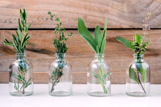 Bottle of essential oil with herbs rosemary, sage,holy basil and thyme  set up on old wooden background .