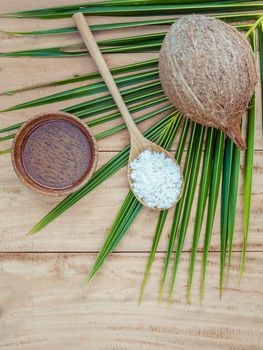 Coconut oil , coconut powder and coconut on coconut leaves set up on brown wooden background for alternative therapy.