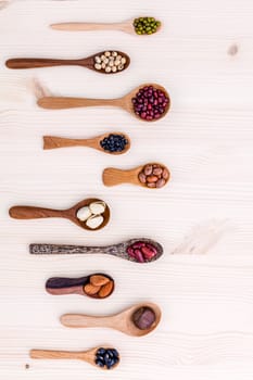 Assortment of beans and lentils in wooden spoon set up on wooden background. mung bean,soybean, red kidney bean , black bean ,red bean ,almonds ,pistachio,chestnut and brown pinto beans .