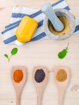 Dried mustard seeds black and yellow  with turmeric powder in wooden spoons and mustard poder in the mortar on rustic wood background .Top view with copy space.