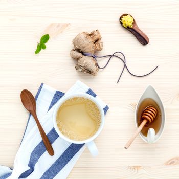The cup of ginger tea with ginger roots , honey and mint on rustic wooden table.