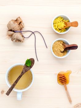 The cup of ginger tea with ginger roots , honey and mint on rustic wooden table.