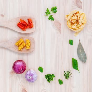 Italian food concept pasta with vegetables olive oil  with spices herbs sage,parsley holy basil and basil set up with wooden background.