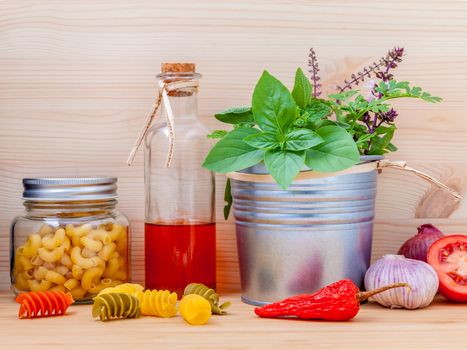 Italian food concept pasta with vegetables olive oil  with spices herbs sage,parsley holy basil and basil set up with wooden background.