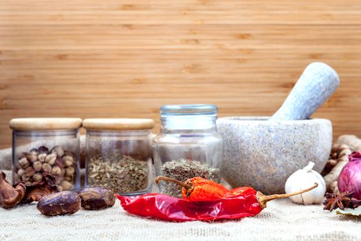 Assortment of spices ingredients of thai popular food red curry with mortar set up on wooden table.