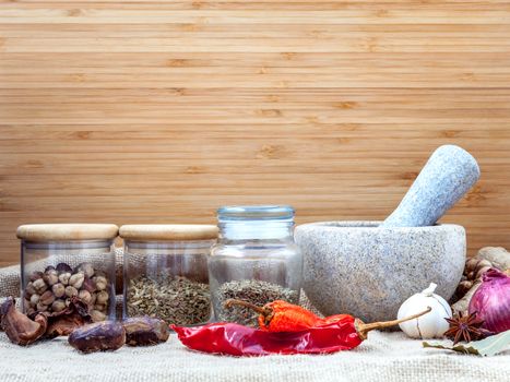 Assortment of spices ingredients of thai popular food red curry with mortar set up on wooden table.