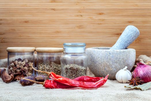 Assortment of spices ingredients of thai popular food red curry with mortar set up on wooden table.