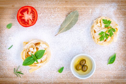 Italian food concept pasta with vegetables olive oil and spices herbs parsley , basil ,bay leaves and rosemary set up with white powder on wooden background.