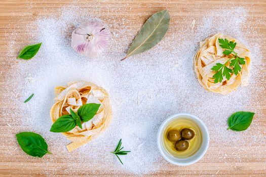 Italian food concept pasta with vegetables olive oil and spices herbs parsley , basil ,bay leaves and rosemary set up with white powder on wooden background.