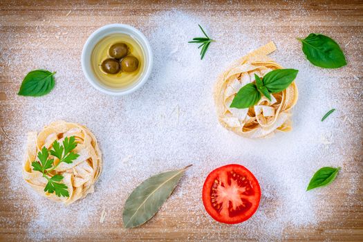 Italian food concept pasta with vegetables olive oil and spices herbs parsley , basil ,bay leaves and rosemary set up with white powder on wooden background.