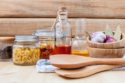 Italian food concept dried pasta with vegetables ,olive oil and spices herbs parsley , basil  and rosemary set up with white cheese on wooden background.