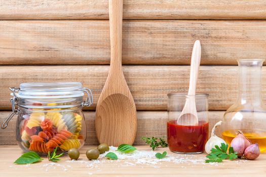 Italian food concept dried pasta with vegetables ,olive oil and spices herbs parsley , basil  and rosemary set up with white cheese on wooden background.