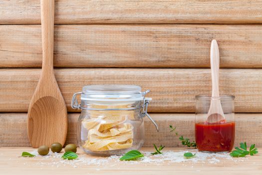 Italian food concept dried pasta with vegetables and spices herbs parsley , basil  and rosemary set up with white cheese on wooden background.