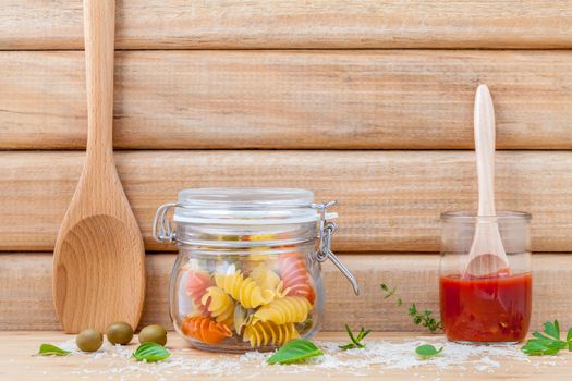 Italian food concept dried pasta with vegetables ,olive oil and spices herbs parsley , basil  and rosemary set up with white cheese on wooden background.