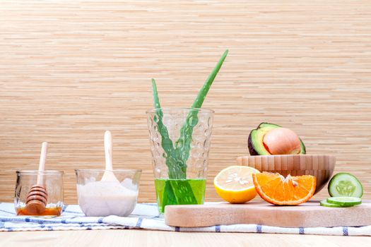 Homemade skin care and body scrub with natural ingredients avocado ,aloe vera ,lemon,cucumber ,orange ,apple, lime and honey set up on on  wooden background.