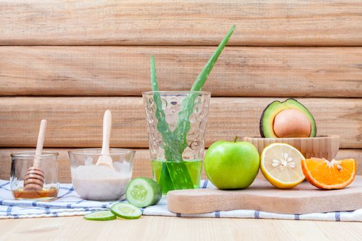 Homemade skin care and body scrub with natural ingredients avocado ,aloe vera ,lemon,cucumber ,orange ,apple, lime and honey set up on on  wooden background.