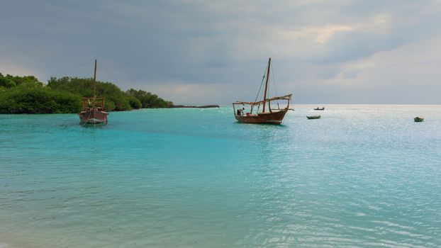 Anchored wooden dhow boats on the amazing turquoise water in the Indian ocean  Zanzibar, Tanzania.