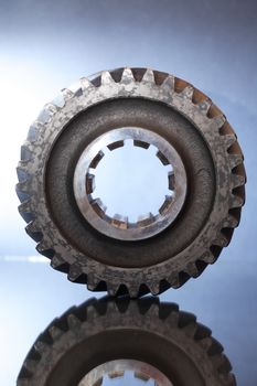 Industrial concept. One old rusty gear on gray background with reflection