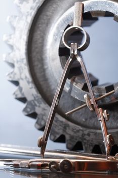 Industrial concept. Divider near old gear on glass surface against gray background