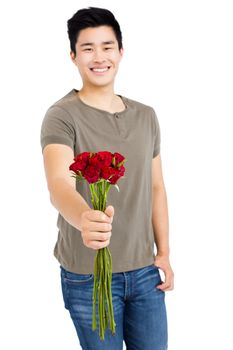 Portrait of a happy young man holding bunch of red roses on white background