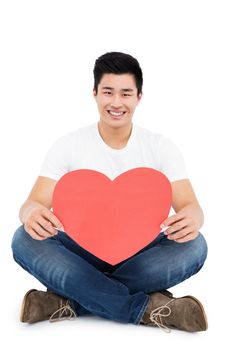 Young man holding heart shape on white background