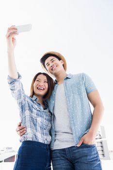 Happy young couple taking a selfie on smartphone outdoors