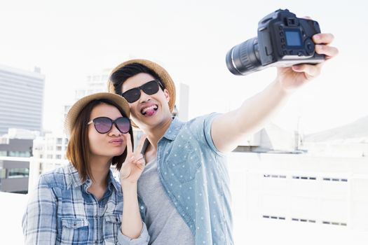 Happy young couple clicking a picture on camera outdoors