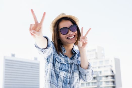 Happy young woman doing a v sign outdoors