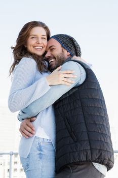 Happy couple cuddling each other and smiling outdoors