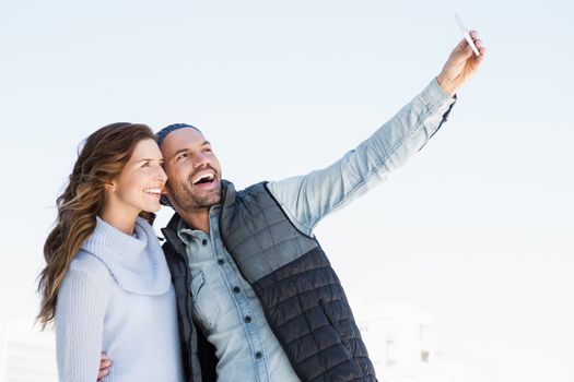 Young happy couple taking selfie on mobile phone outdoors