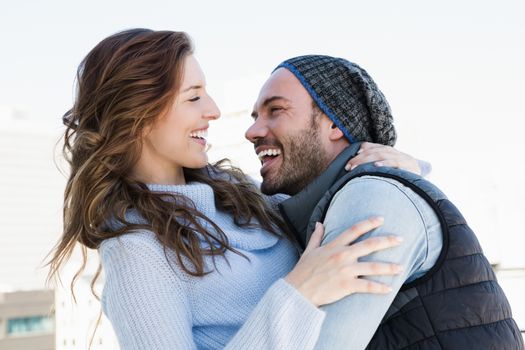 Happy young couple cuddling each other and smiling outdoors