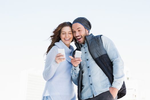 Happy young couple using mobile phone outdoors