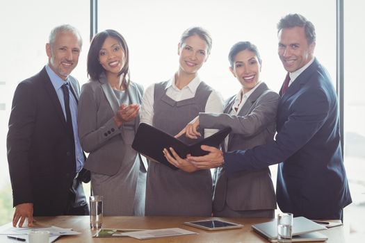 Businesswoman looking at organizer and interacting with team in office