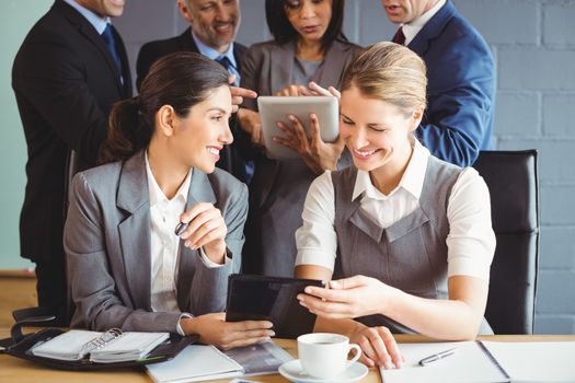Businesswomen using digital tablet and interacting in conference room