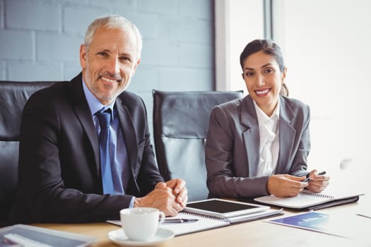 Portrait of businessman and businesswoman sitting in conference room