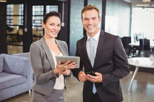 Portrait of happy businessman and businesswoman with digital tablet and mobile phone