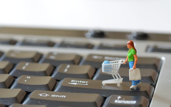Miniature shopper with shopping cart on a computer keyboard