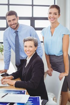 Portrait of confident business people at computer desk in office