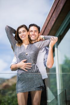 Low angle view of romantic young couple embracing in balcony at resort