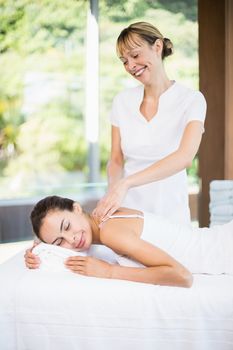 Happy female masseur massaging woman at health spa