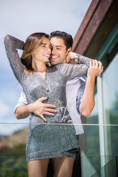 Happy romantic young couple embracing in balcony at resort