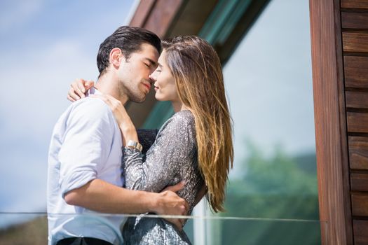 Low angle view of romantic young couple kissing in balcony at resort