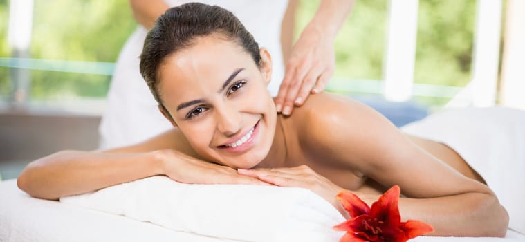 Close-up portrait of young woman smiling while receiving massage at health spa