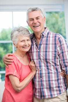 Happy senior couple embracing and standing at home 