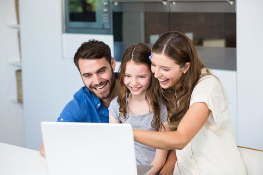 Family laughing while looking at laptop at home 