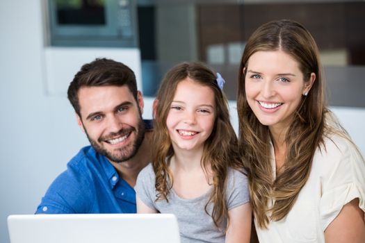 Portrait of smiling family with laptop at home 